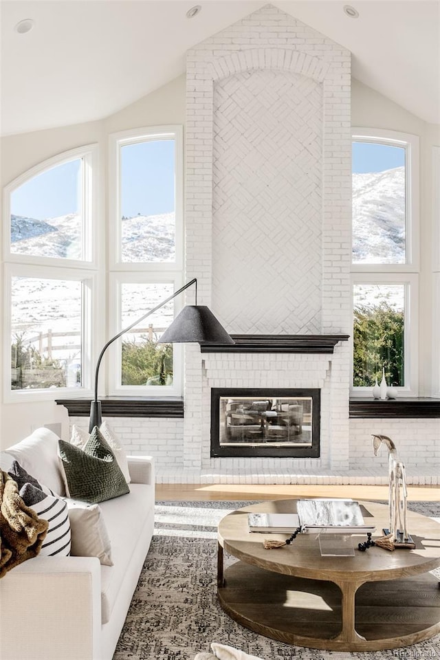 interior space with plenty of natural light, a fireplace, a mountain view, and vaulted ceiling