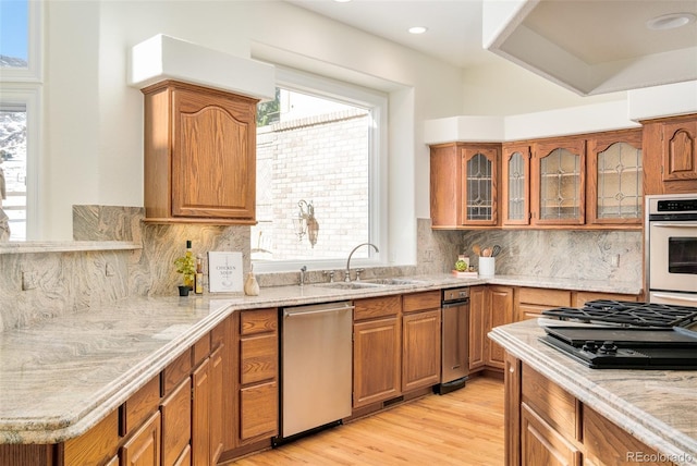 kitchen with stainless steel appliances, sink, backsplash, and light wood-type flooring