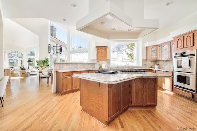 kitchen with tasteful backsplash, a kitchen island, light wood-type flooring, and double oven