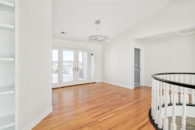 empty room featuring hardwood / wood-style flooring, vaulted ceiling, and french doors