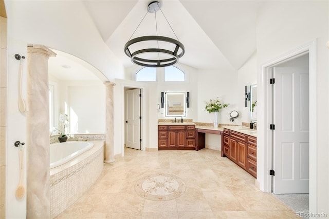 bathroom featuring lofted ceiling, tiled tub, vanity, and decorative columns