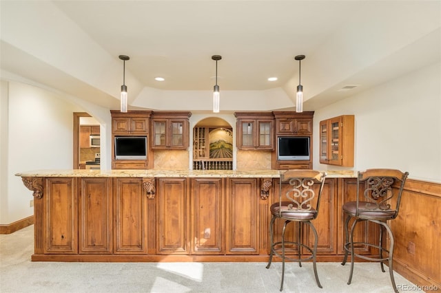 kitchen featuring tasteful backsplash, kitchen peninsula, pendant lighting, light colored carpet, and light stone countertops