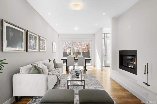 living room with baseboards, recessed lighting, a glass covered fireplace, and light wood-style floors