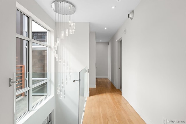 hall with recessed lighting, a notable chandelier, light wood-style flooring, and baseboards