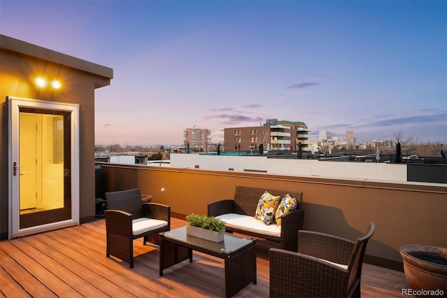 deck at dusk with an outdoor living space and a city view