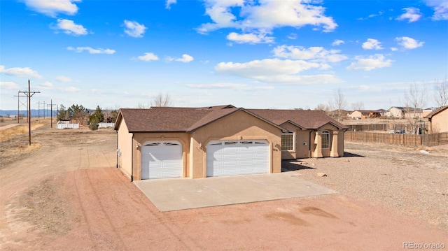 single story home with concrete driveway, stucco siding, fence, an attached garage, and a shingled roof