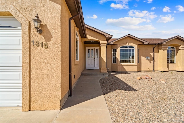 doorway to property with stucco siding and a garage