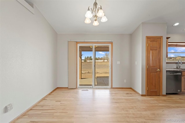 unfurnished dining area with an inviting chandelier, baseboards, and light wood finished floors