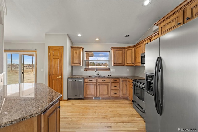 kitchen with light wood-style flooring, plenty of natural light, brown cabinets, appliances with stainless steel finishes, and a sink