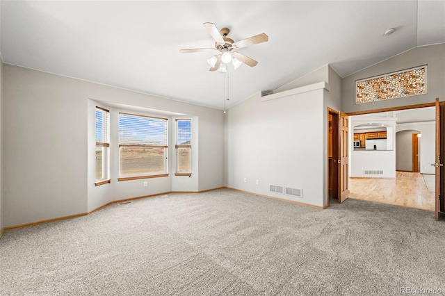 carpeted spare room featuring a ceiling fan, arched walkways, vaulted ceiling, and visible vents
