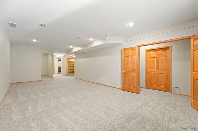 finished basement featuring recessed lighting, light carpet, arched walkways, and visible vents
