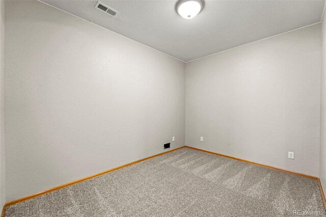 spare room featuring baseboards, visible vents, and carpet flooring