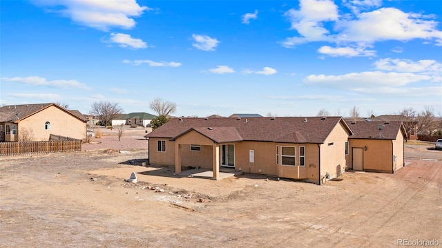 back of property featuring a residential view, stucco siding, fence, and a patio