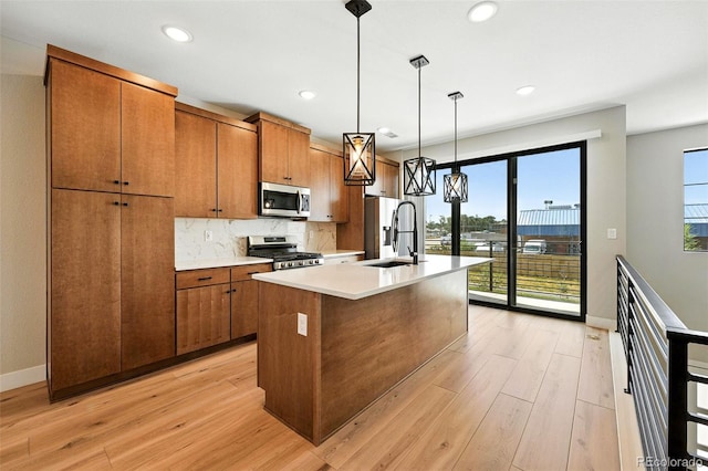 2074 S Holly St Unit 2, Denver, CO 80222 - kitchen with appliances with stainless steel finishes, brown cabinetry, light wood-style floors, an island with sink, and recessed lighting