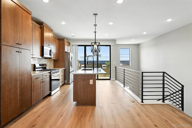2074 S Holly St Unit 2, Denver, CO 80222 - kitchen featuring appliances with stainless steel finishes, recessed lighting, a center island with sink, light countertops, and decorative light fixtures