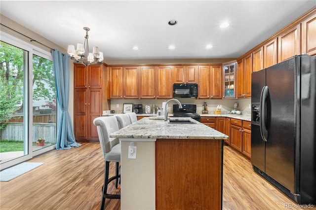 9631 S Dover Way, Littleton, CO 80127 - kitchen featuring black appliances, brown cabinetry, a sink, a chandelier, and light stone counters