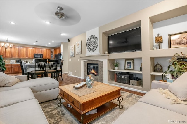 9631 S Dover Way, Littleton, CO 80127 - living area with wood finished floors, baseboards, ceiling fan, a tiled fireplace, and built in shelves