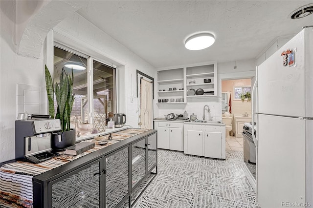 kitchen with sink, built in features, a textured ceiling, white cabinets, and white fridge