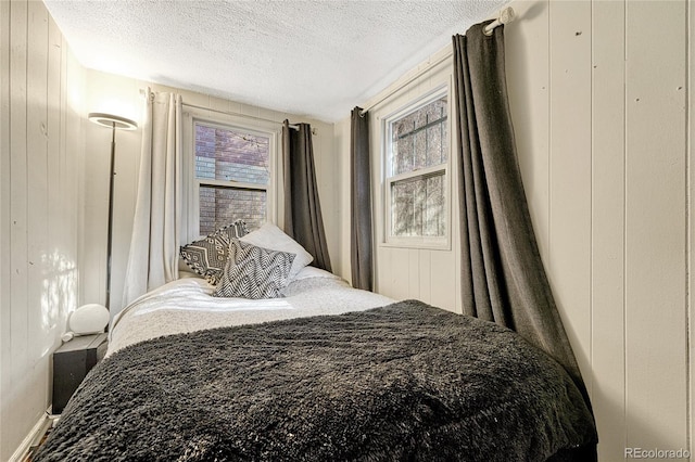 bedroom featuring a textured ceiling and wood walls