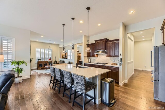14969 Elsinore Ave, Parker, CO 80134 - kitchen with a sink, hardwood / wood-style flooring, appliances with stainless steel finishes, a breakfast bar, and recessed lighting
