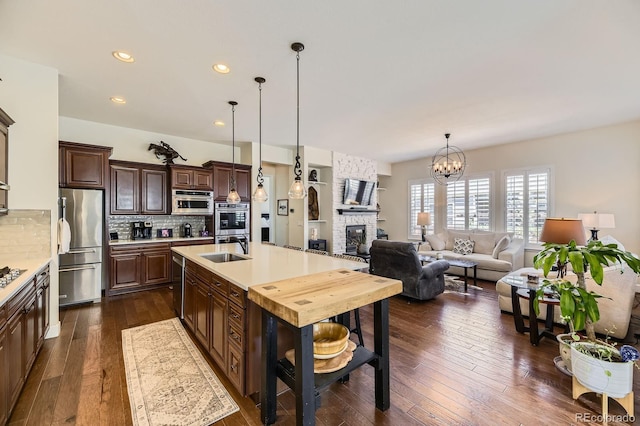 14969 Elsinore Ave, Parker, CO 80134 - kitchen with appliances with stainless steel finishes, a sink, light countertops, a fireplace, and decorative backsplash