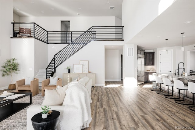 living room with a high ceiling, hardwood / wood-style flooring, and sink