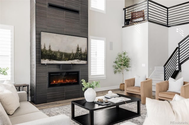 living room with a fireplace, a towering ceiling, and light hardwood / wood-style floors