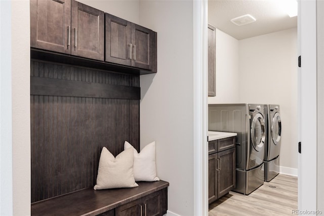 washroom featuring cabinets, light hardwood / wood-style floors, and washing machine and dryer