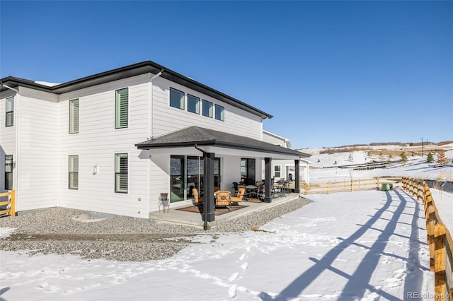 snow covered back of property featuring a patio