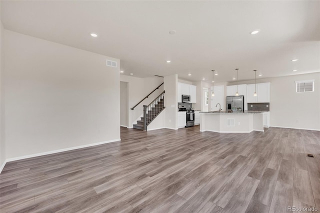 3325 Umber Cir, Castle Rock, CO 80109 - unfurnished living room with a sink, recessed lighting, light wood-style floors, stairway, and baseboards