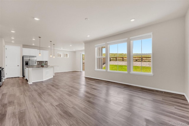 3325 Umber Cir, Castle Rock, CO 80109 - unfurnished living room with wood finished floors, recessed lighting, a sink, and baseboards