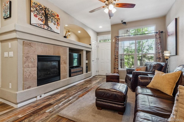 living room featuring a tile fireplace, ceiling fan, and hardwood / wood-style flooring