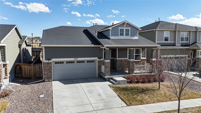 craftsman house with fence, driveway, covered porch, stone siding, and a residential view