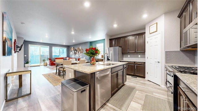 kitchen featuring dark brown cabinetry, a healthy amount of sunlight, stainless steel appliances, and tasteful backsplash