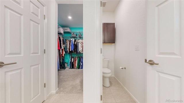 bathroom with tile patterned flooring, visible vents, toilet, and a walk in closet