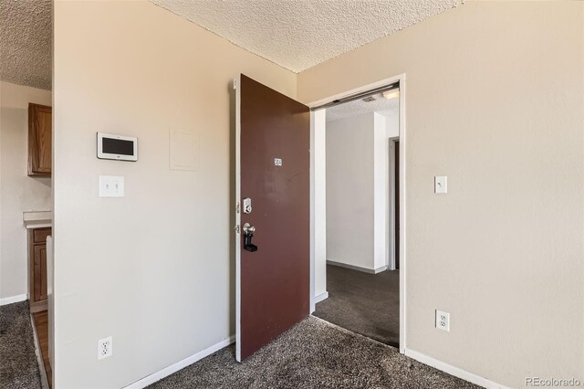 hallway featuring a textured ceiling, carpet floors, and baseboards