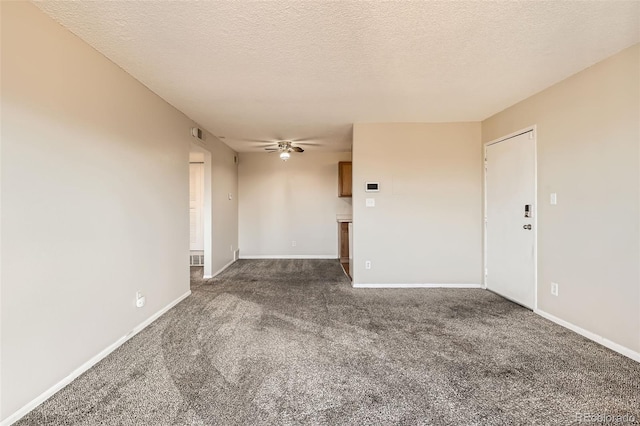 spare room featuring a textured ceiling, ceiling fan, dark carpet, and baseboards