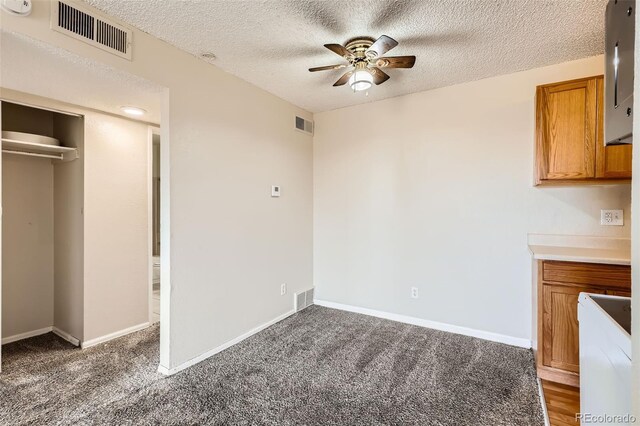 unfurnished dining area featuring a ceiling fan, visible vents, a textured ceiling, and baseboards