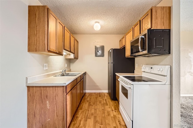 kitchen featuring white range with electric stovetop, stainless steel microwave, brown cabinets, light countertops, and a sink