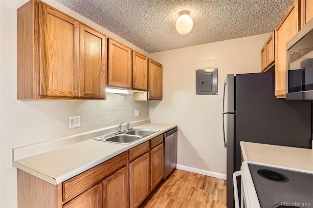 kitchen with electric panel, stainless steel appliances, a textured ceiling, light countertops, and a sink