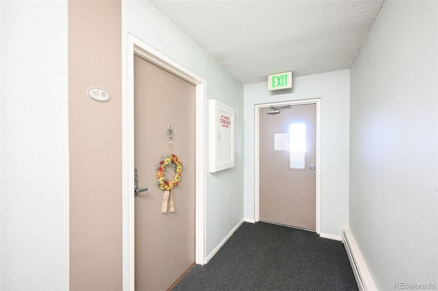 hall featuring a textured ceiling, dark colored carpet, a baseboard radiator, and baseboards