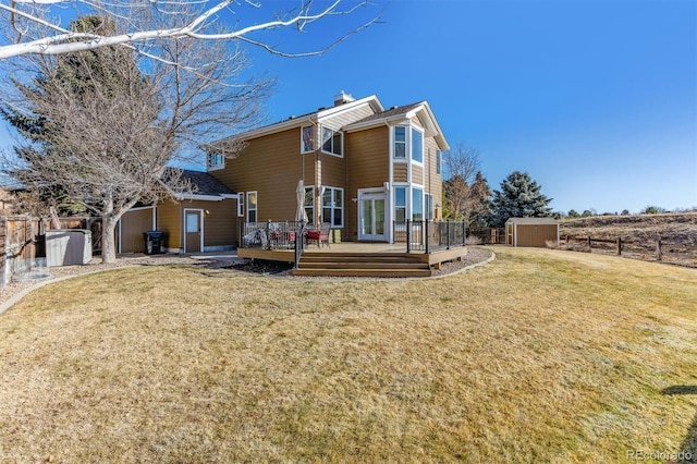 back of property featuring a shed, a deck, and a lawn