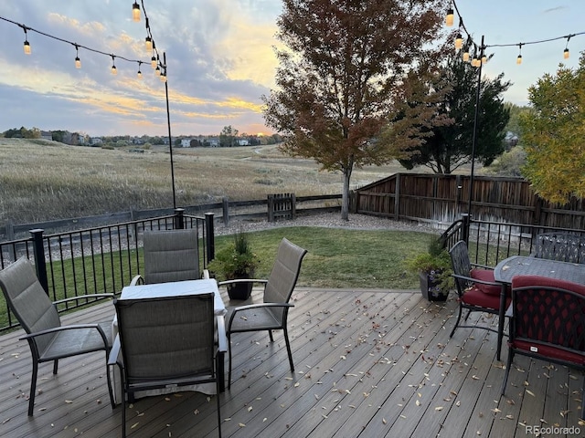 deck at dusk featuring a lawn