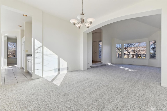 unfurnished living room featuring light carpet and a notable chandelier