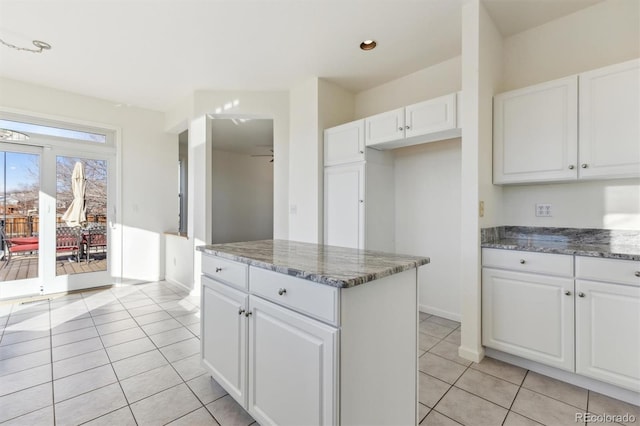 kitchen with dark stone countertops, ceiling fan, white cabinets, and light tile patterned floors