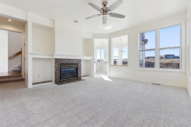 unfurnished living room featuring ceiling fan, a fireplace, and light carpet