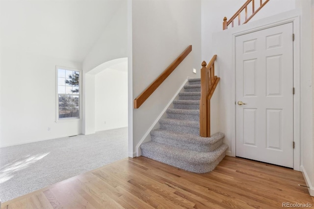 stairs featuring hardwood / wood-style flooring and high vaulted ceiling