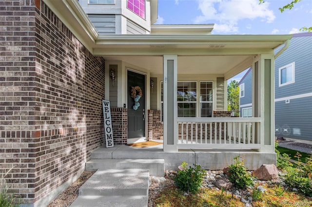 6040 Virgil St, Arvada, CO 80403 - doorway to property featuring brick siding and a porch