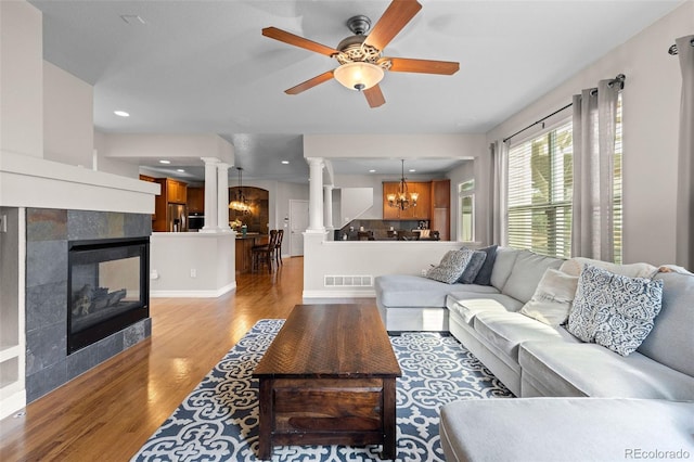 6040 Virgil St, Arvada, CO 80403 - living area with ornate columns, light wood-type flooring, a chandelier, a ceiling fan, and a tiled fireplace