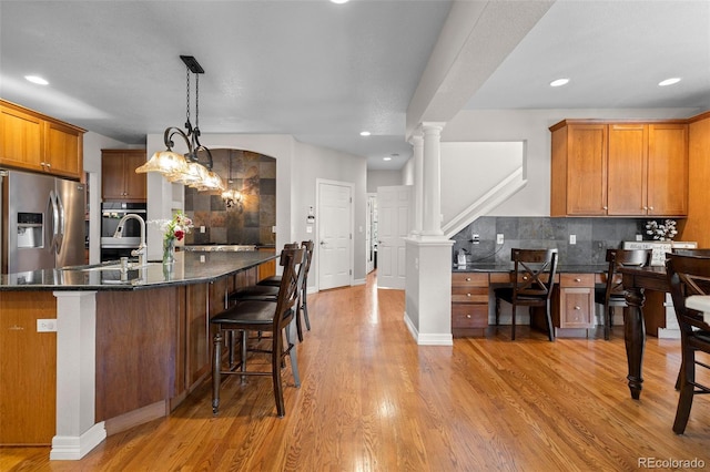 6040 Virgil St, Arvada, CO 80403 - kitchen with stainless steel refrigerator with ice dispenser, a sink, backsplash, a breakfast bar area, and brown cabinetry